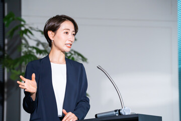 プレゼンをするスーツを着たショートヘアーの日本人女性