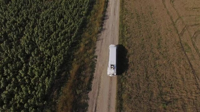 white suv limousine rides on the road in summer field. Aerial shot