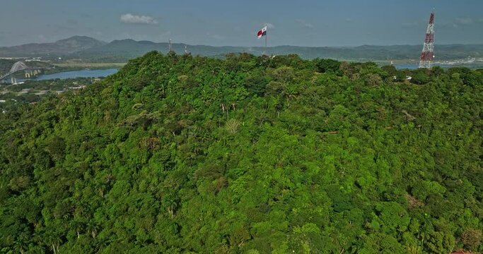 Panama City Aerial v64 cinematic dolly in flyover ancon hill capturing wavy national flag, reveals water canal, port of balboa and commercial shipyard harbor - Shot with Mavic 3 Cine - March 2022
