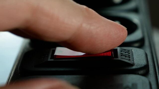 human figer press and off red lighting outlet switch on black Electric Extension Cord, closeup