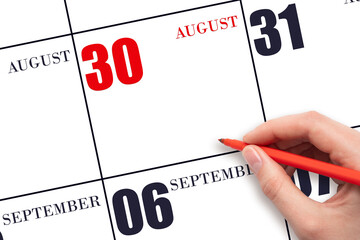 A hand holding a red pen and pointing on the calendar date August 30. Red calendar date, copy...