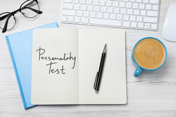 Notebook with text Personality Test, computer keyboard and cup of coffee on white wooden desk, flat...