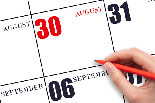 A hand holding a red pen and pointing on the calendar date August 30. Red calendar date, copy space, mockup.