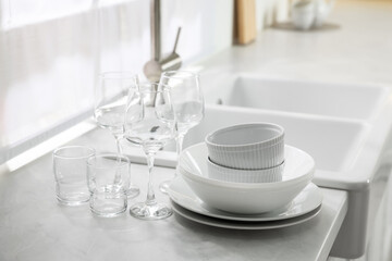 Different clean dishware and glasses on countertop near sink in kitchen