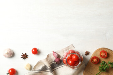 Pickling jar with fresh ripe cherry tomatoes and spices on white wooden table, flat lay. Space for text