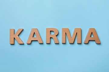 Fototapeta na wymiar Word Karma made with wooden letters on light blue background, top view
