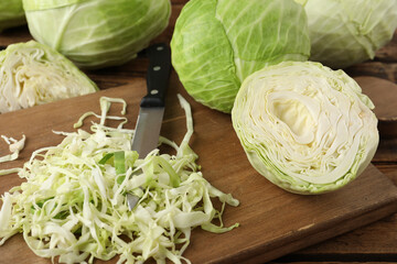 Chopped ripe cabbage and knife on wooden board, closeup