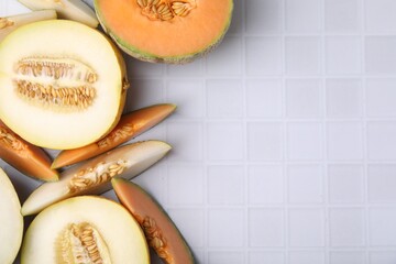 Tasty colorful ripe melons on white checkered table, flat lay. Space for text