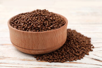 Bowl with buckwheat tea granules on white wooden table, closeup