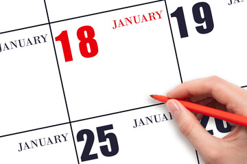 A hand holding a red pen and pointing on the calendar date January 18. Red calendar date, copy...