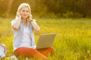 Euphoric woman searching job with a laptop in an urban park in summer.