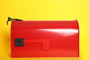 Closed red letter box on yellow background, closeup
