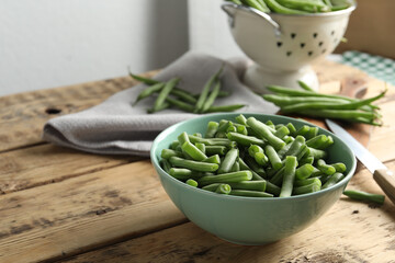 Fresh green beans in bowl on wooden table, space for text