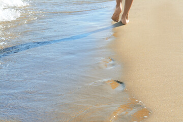 Woman walking on sandy beach near sea, closeup. Space for text