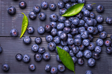Blueberries with green leaves, on a dark blue wooden background. Close-Up. Healthy food. Diet. Top...