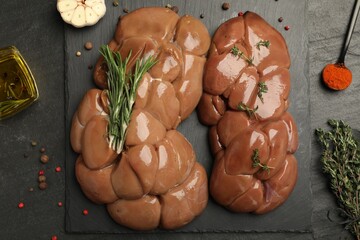 Fresh raw kidneys with seasonings on black table, flat lay