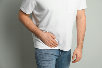 Man suffering from acute appendicitis on light grey background, closeup