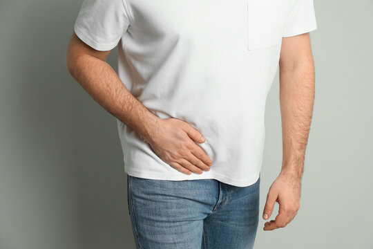 Man suffering from acute appendicitis on light grey background, closeup