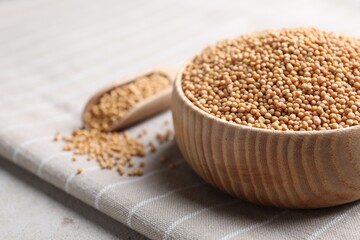 Mustard seeds in wooden bowl on table, closeup. Space for text