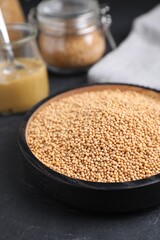Mustard seeds in black bowl on grey table