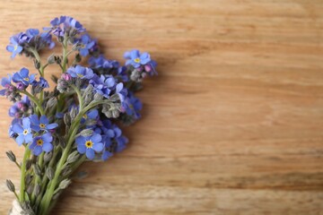Beautiful blue forget-me-not flowers on wooden table, top view. Space for text