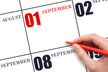 A hand holding a red pen and pointing on the calendar date September 1. Red calendar date, copy space, mockup.