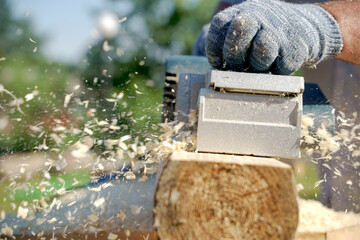 a carpenter works with an electric pipe on a sunny day