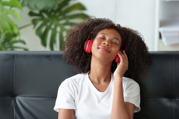 Young women are cute and charming and bright, wearing headphones, listening to music happily, enjoying listening to music at home in their free time on vacation.