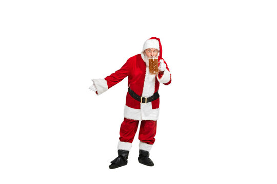 Portrait of senior man in image of Santa Claus sipping lager foamy beer isolated over white background.