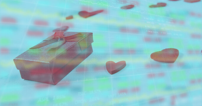 Image of gift box and heart shapes over moving graphs and trading board