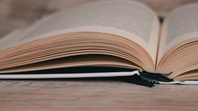 Turning pages in a white book close up slow mo. Reading a book, intelligence. Pages flow one after another. Women's hands leaf through a book.