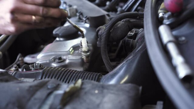 young auto mechanic repairs a car engine. spark plug replacement.