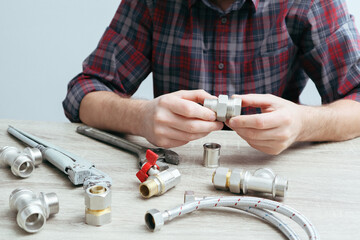 Plumber measures the size of fitting before connecting water pipe. Plumber connects fittings while repairing equipment. Close-up of hands of the master plumber.
