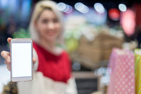 Blurred mockup image of a woman holding and showing a mobile phone with blank white screen