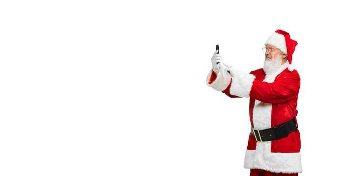 Portrait of senior man in image of Santa Claus posing with phone isolated over white background