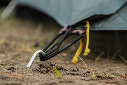 The peg from the tent is sticking out of the ground. The tent is strapped to it