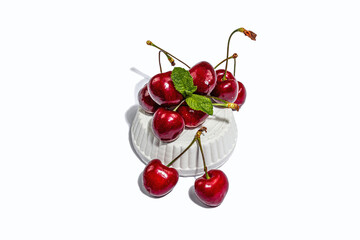 Ripe sweet cherries with fresh mint leaves isolated on white background. Trendy beton stand