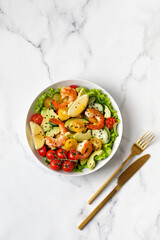 Fresh seafood salad with prawns, shrimps, avocado, cucumber on white marble background. Healthy diet concept.