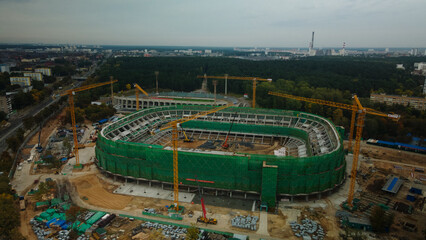 Building a stadium in a big city. Construction site among urban areas. Aerial photography.