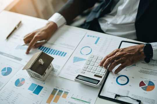 Bank loan workers are using calculators to calculate home loan interest rates for customers to assess their investment capabilities using key documents at working