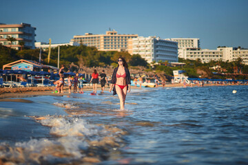 Young woman in red bikini walking at the Ayia Napa beach