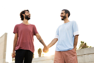 Gay couple walking together. Two man holding hands at the street.