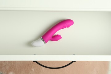 Modern vibrator in open white drawer, top view. Sex toys