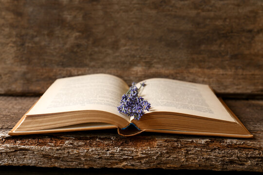 Open book with beautiful dried flowers on wooden table