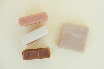 Organic soap made with natural herbal ingredients and essential oils over light yellow background. Making vegan skincare products and cosmetics at home. Mockup image