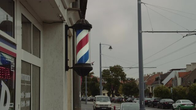 A barber pole calling for people at street. Vintage Barbershop. Salon. A hairdressing company with entrance from the street. Establishing Shot 4K Video.