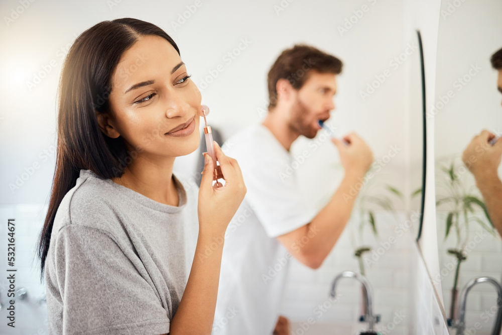 Canvas Prints Makeup, face and beauty with a woman using cosmetics in the bathroom at home with her man in the background. Cosmetic, skin and care with an attractive young female and her boyfriend in their house