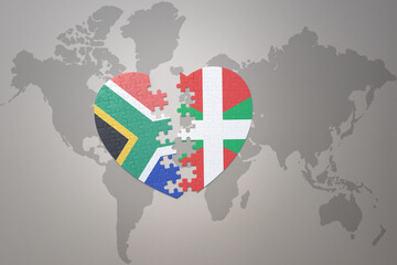 puzzle heart with the national flag of south africa and basque country on a world map background. 3D illustration