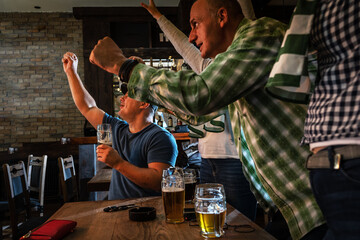 Mature football and soccer fans drinking beer at the pub and celebrating scores.