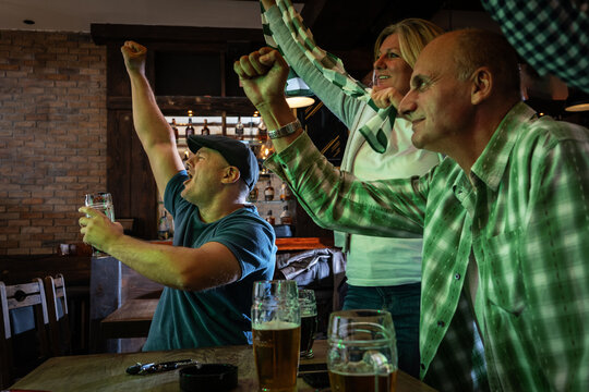 Mature football and soccer fans drinking beer at the pub and celebrating scores.
